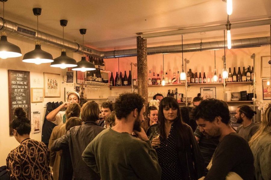This is an image of a busy wine bar with people mingling and drinking.