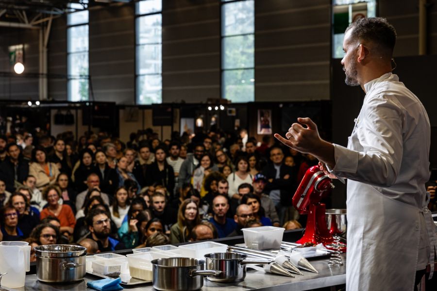 This is an image of a group of people watching a chef on stage make chocolate.