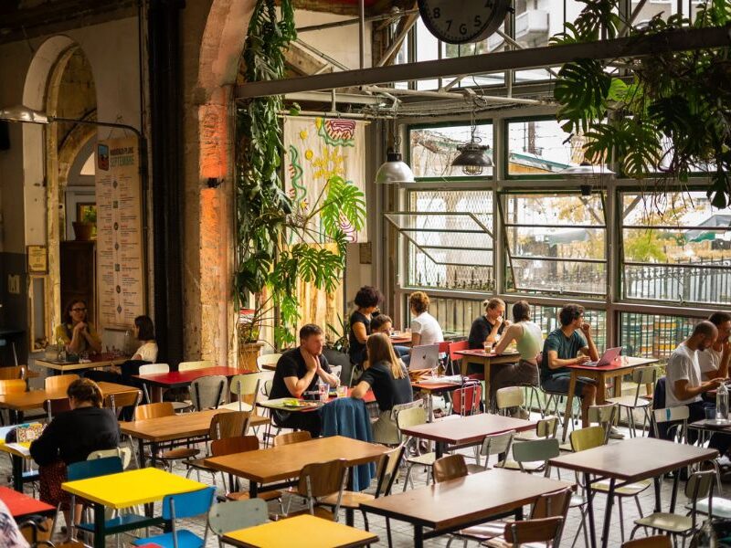 Best Non-Touristy Cafes in Paris: This is an image of a beautiful café with big windows and greenery everywhere.