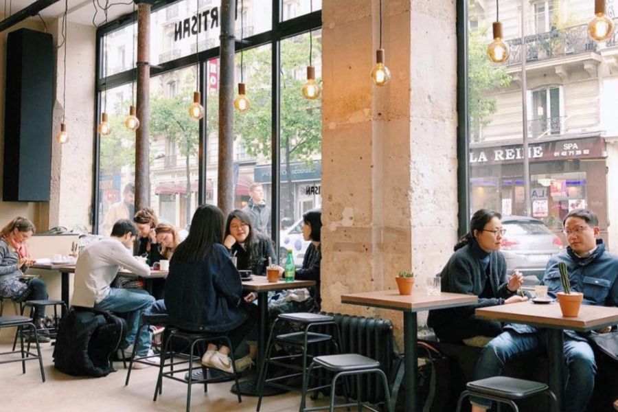 Best Non-Touristy Cafes in Paris: This is an image of the inside of a minimalist cafe with stone walls and clean, simple tables.
