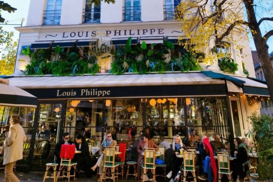 This is an image of a lovely café, which is two-storeys and has lots of greenery around it.