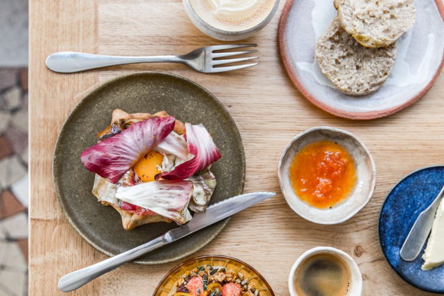 This is an image of a table full of food and a setting of cutlery.
