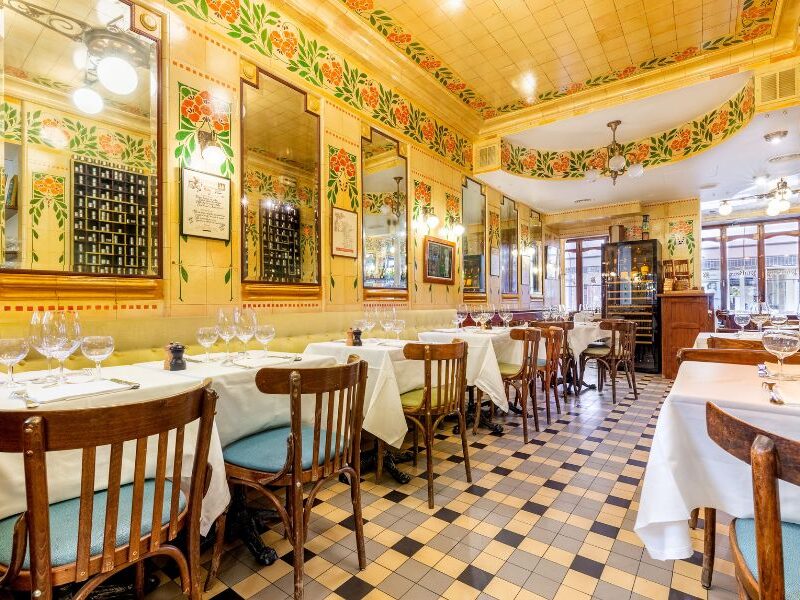 This is an image of a very bright yellow restaurant full of eccentric art and set tables.