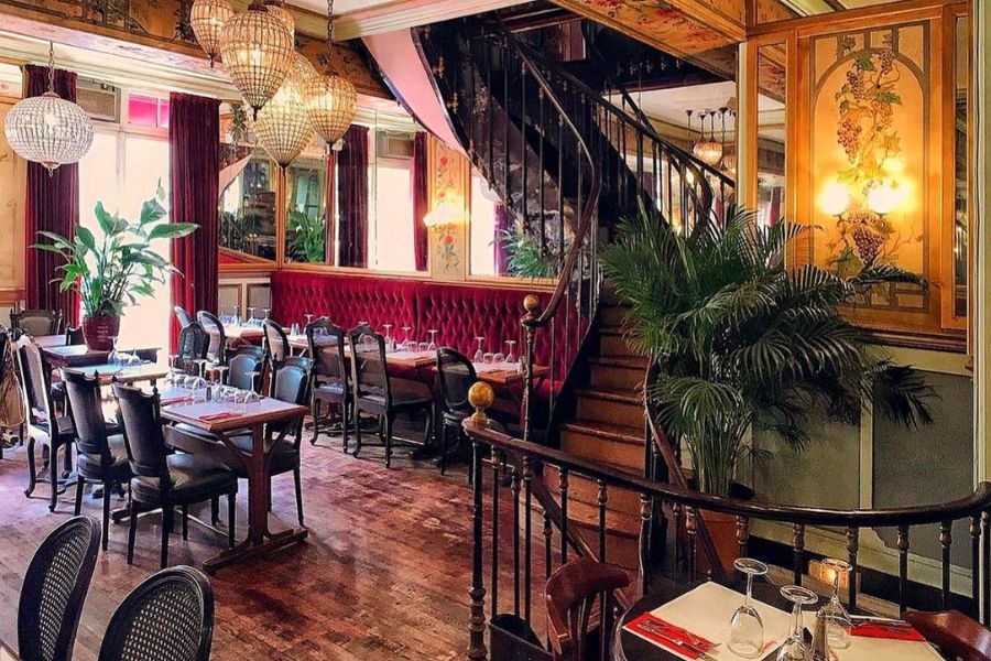 This is an image of a restaurant filled with tables and red, royal interiors.