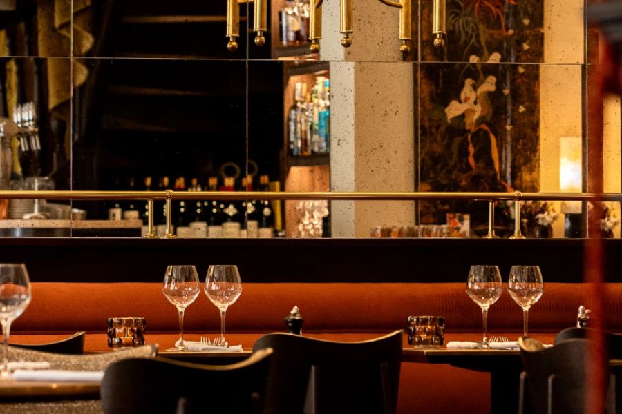 This is an image of a restaurant fitted with tables that have been set with cutlery and wine glasses.
