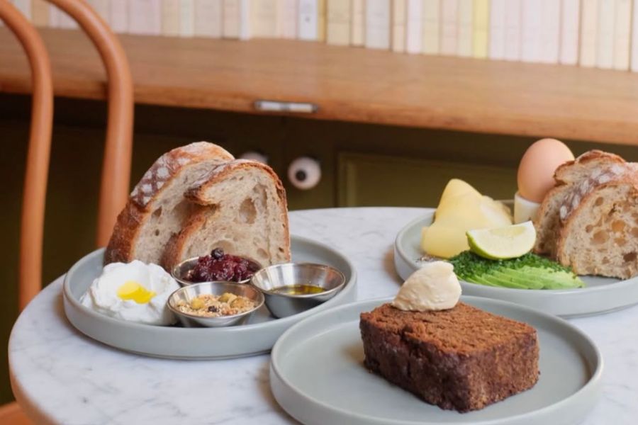 This is an image of some breakfast items on a white marble table, in the background, you can see a bookcase.