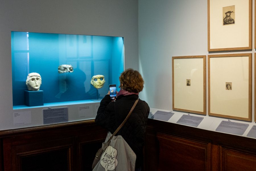 This is an image of a woman taking a photo inside an art gallery full of intricate objects.