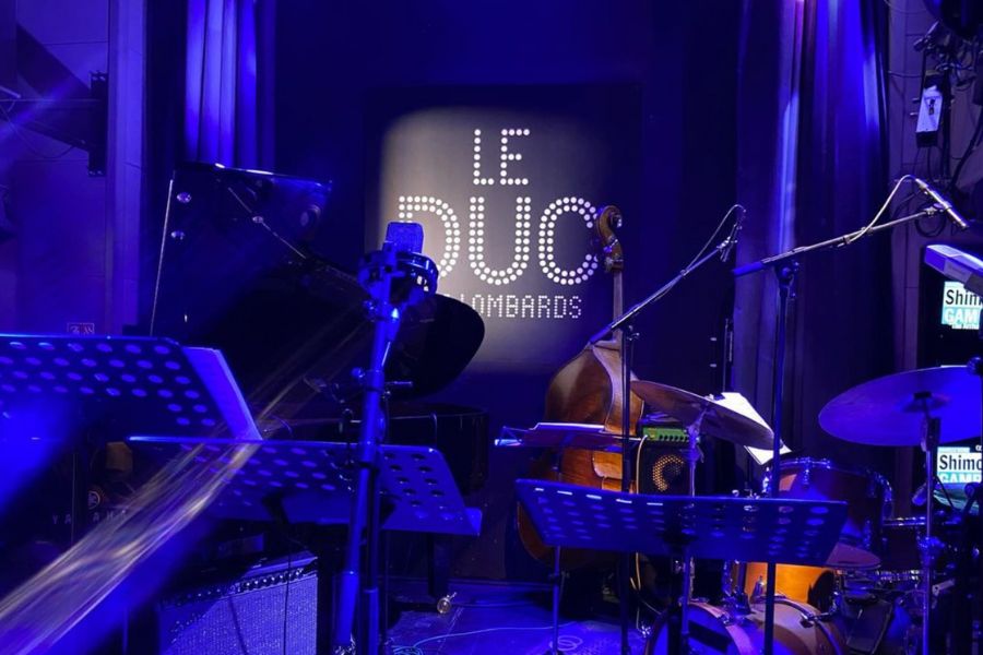 This is an image of a stage with dark blue down lights and musical equipment ready for a show.
