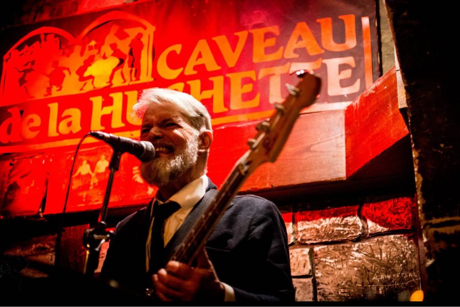 This is an image of a man singing into a mic, playing a guitar on stage.