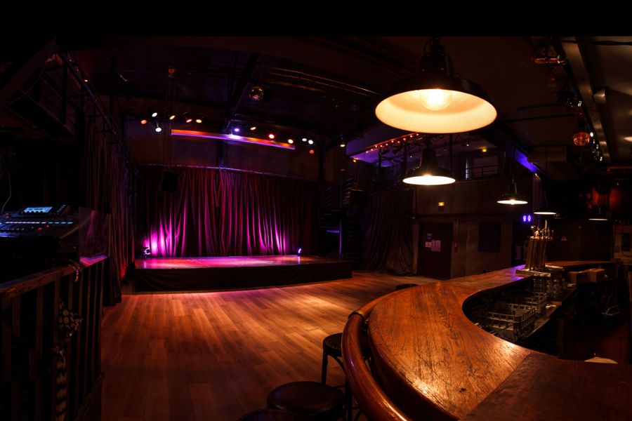 This is an image of a big room with lots of space to dance on the dance floor and a small unoccupied stage.