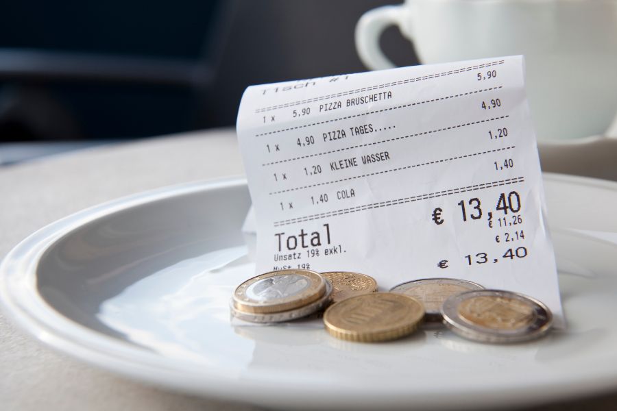 This is an image of a receipt with tips and coins on a plate.