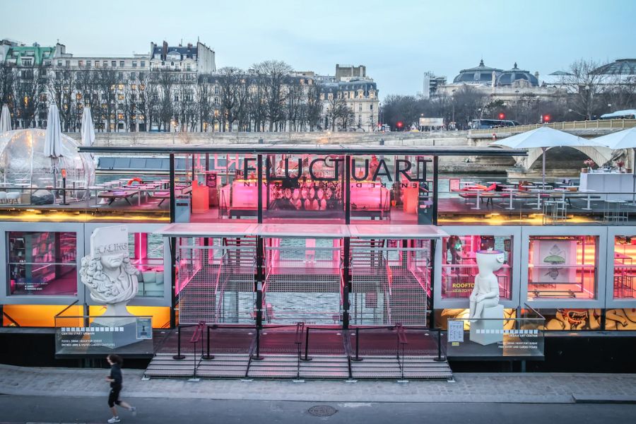 This is an image of a floating bar with lots of seating space and a view of the Seine.
