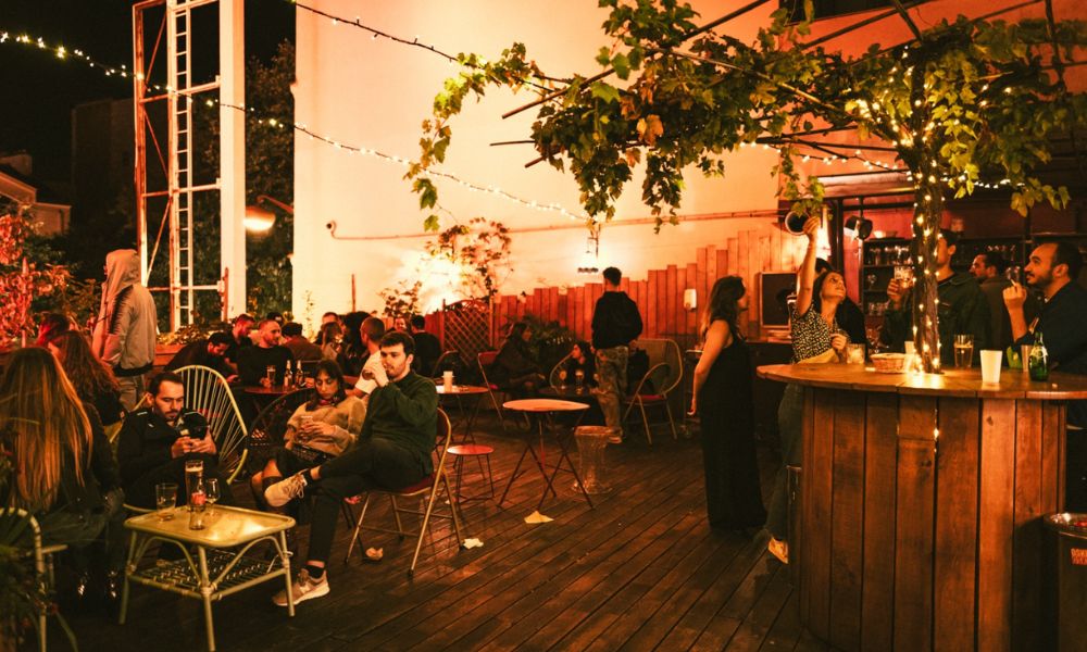 This is an image of a dark terrace with people sitting down drinking and chatting.
