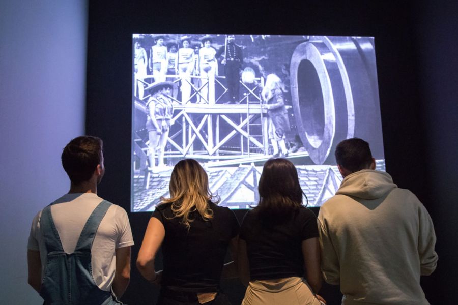 This is an image of four people watching a projected video about old cinema.