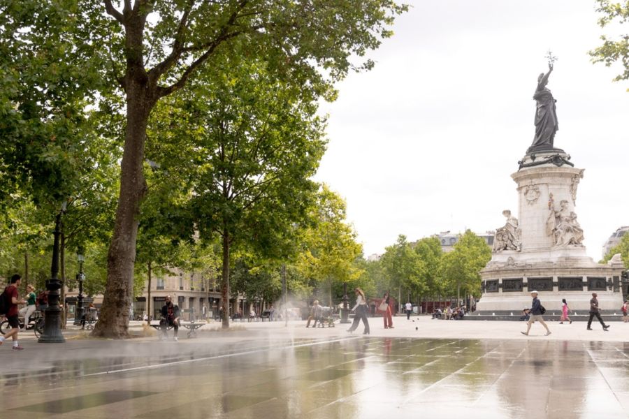 Place de la République on a summer day, with the Marianne statue, mature trees, and water mist jets on the plaza