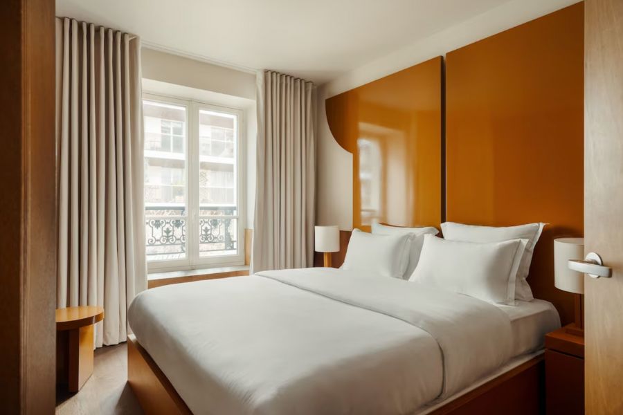 This is a lovely, minimalist apart-hotel in the heart of Paris with a very chic bedroom pictured full of beige bedding and linen.