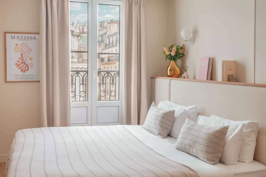 This is a picture of a white, minimalist hotel room in Paris with a Matisse poster.