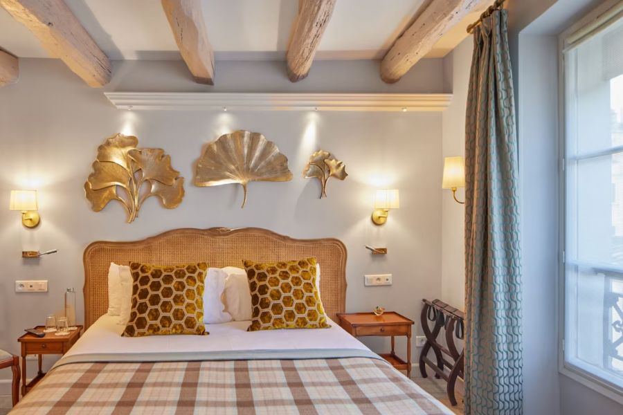 This is an image of a small hotel room in Paris with a double bed and yellow checked sheets.