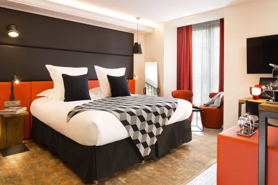 This is an image of a quaint hotel room in Paris with black and red colour accents.