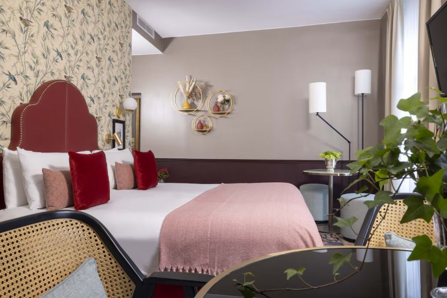 This is an image of a hotel room in Paris with a double bed and a small desk alongside it.