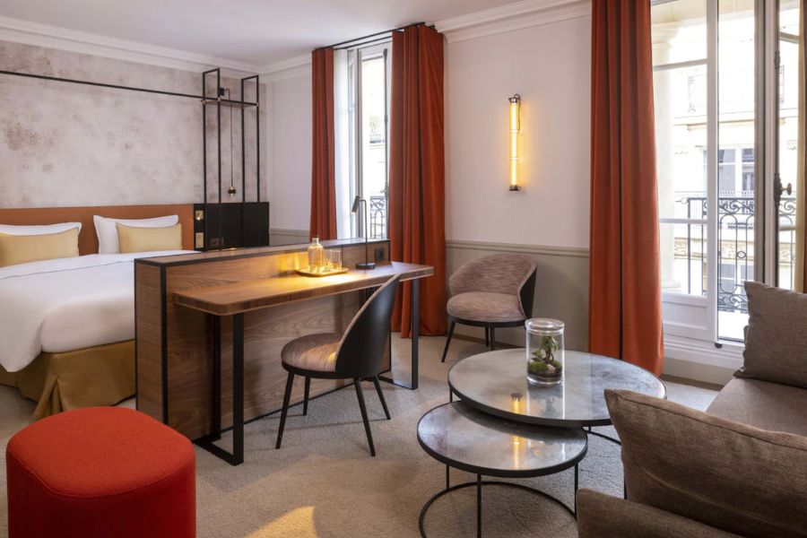 This is an image of a minimalist hotel room in Paris with burnt orange accents.