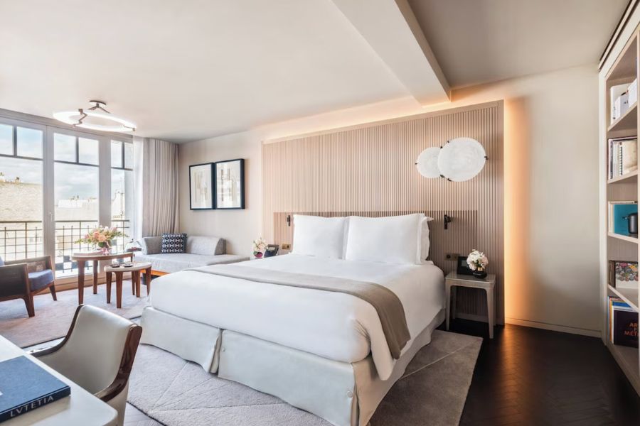 This is an image of a minimalist hotel room in Paris with a double bed and a desk.