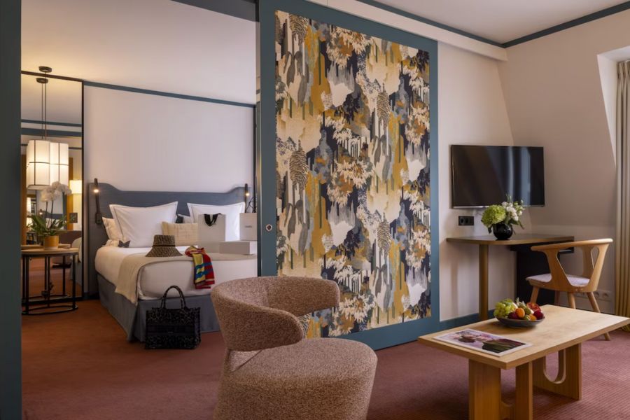 This is an image of a large hotel room with a double bed and a lounge area with a desk and coffee table.
