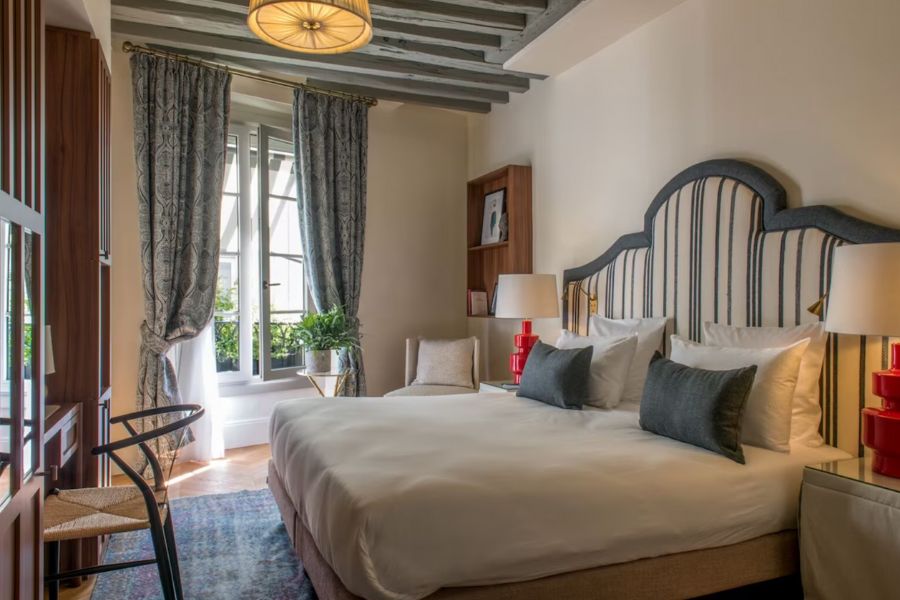 This is an image of a big hotel room in central Paris with a big king-sized bed and big double windows that let in lots of light.