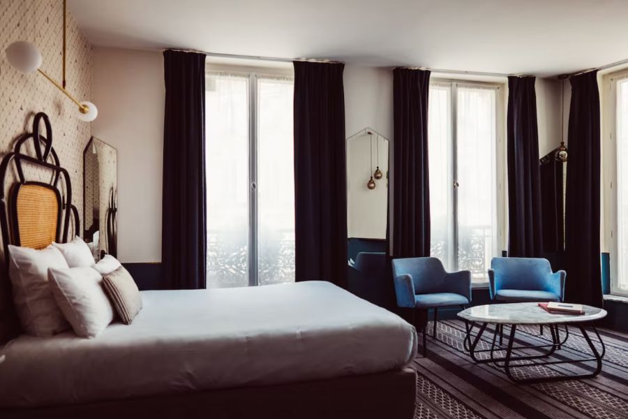 This is an image of a nice hotel room with a double bed and a lounging area with couches and a table.
