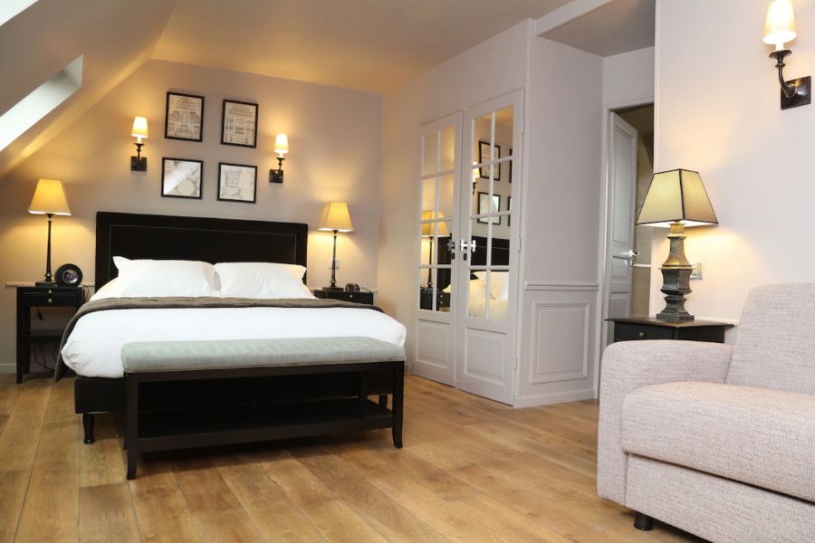 This is an image of a nice hotel room with a double bed and a full length mirror. There is lots of lamps and light.