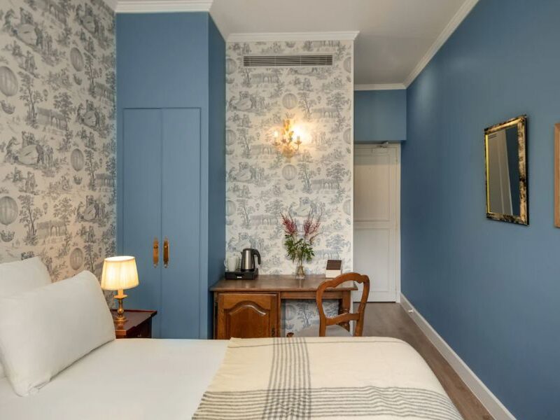 This is a cool, minimalist hotel room in the Latin Quarter of Paris featuring blue accents and white bedding.