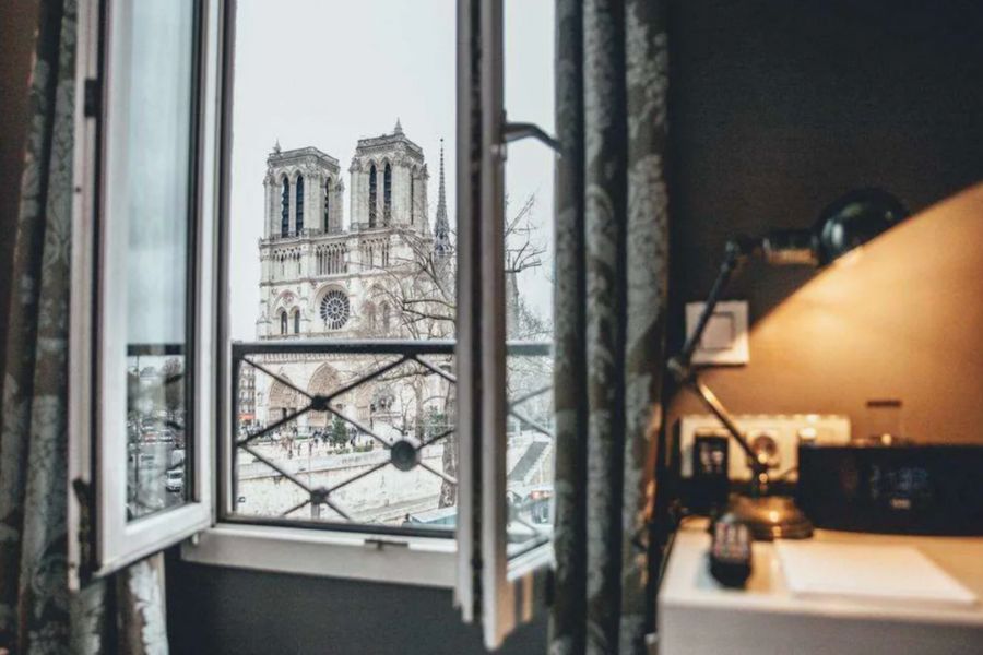 This is a cool hotel room in the Latin Quarter of Paris featuring views of the Notre Dame right outside the window.