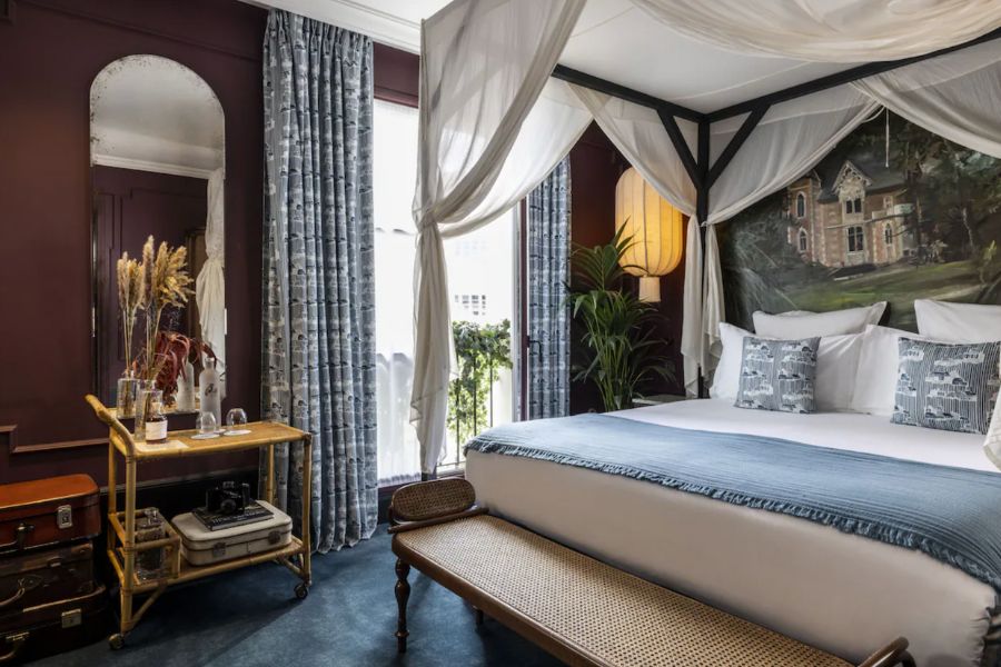 This is a cool, minimalist hotel room in the Latin Quarter of Paris featuring antique decor, blue accents and white bedding.