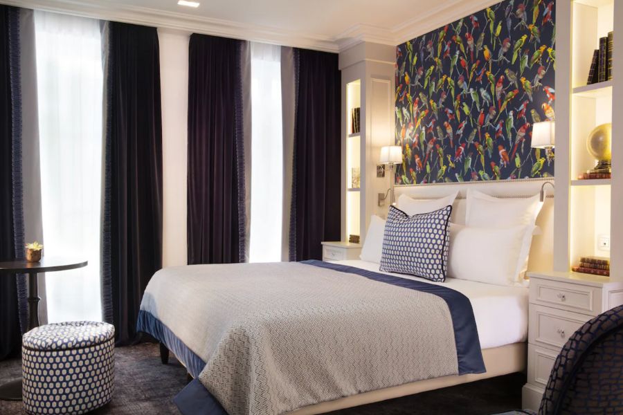This is an image of a hotel room in the Latin Quarter of Paris featuring a double bed and dark curtains.