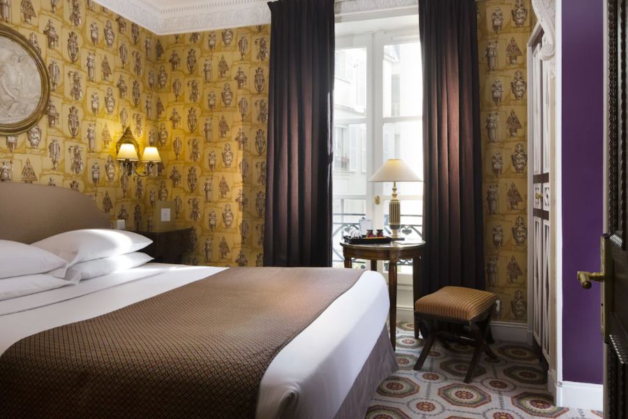 This is an image of a hotel room in the Latin Quarter of Paris with a brown patterned feature wall and brown curtains to match.