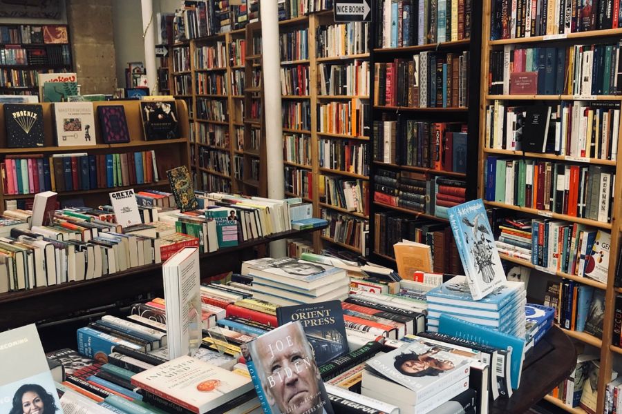 This is an image of a bookstore with lots of books lining the walls and books laid out on tables.