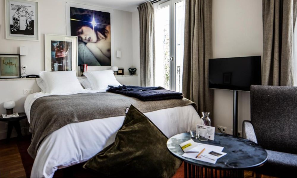 Best Paris hotels for solo travelers: This is an image of a luxe hotel room with lots of art, a large bed and a small coffee table.