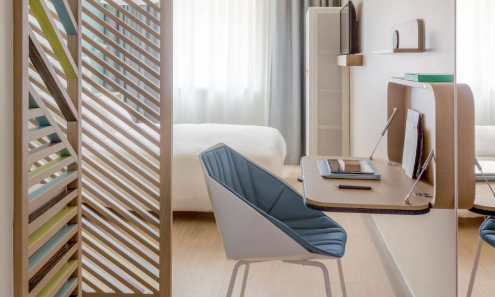 Best Paris hotels for solo travelers: This is an image of a small hotel room with a fold-out desk and small double bed. There is also a wardrobe and ensuite.