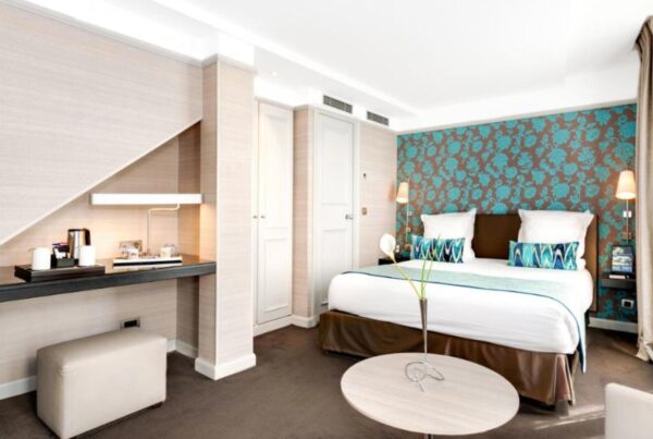 This is an image of a beautiful hotel room with a mini kitchenette, a large double bed and a blue and brown feature wall.