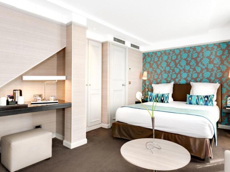 This is an image of a beautiful hotel room with a mini kitchenette, a large double bed and a blue and brown feature wall.