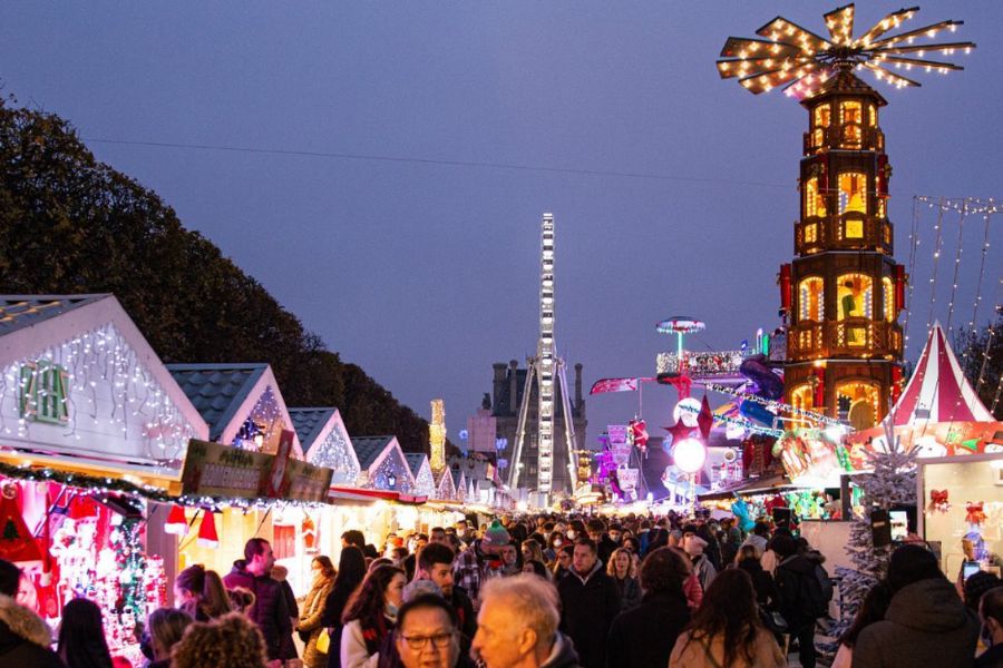 This is an image of a Christmas market with lots of lights and mini houses. It is quite crowded.