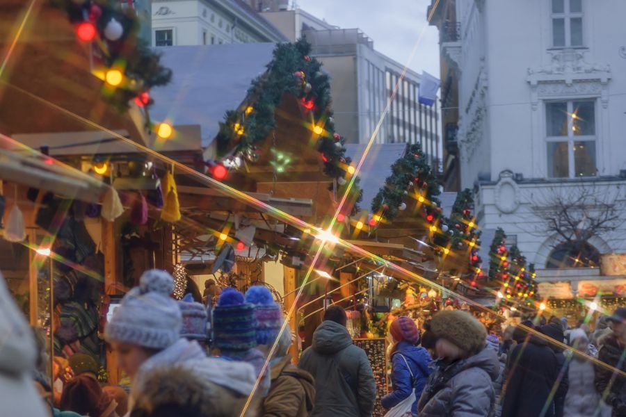 This is an image of a Christmas market with lots of little stalls and crowds dressed in beanies and warm clothes.