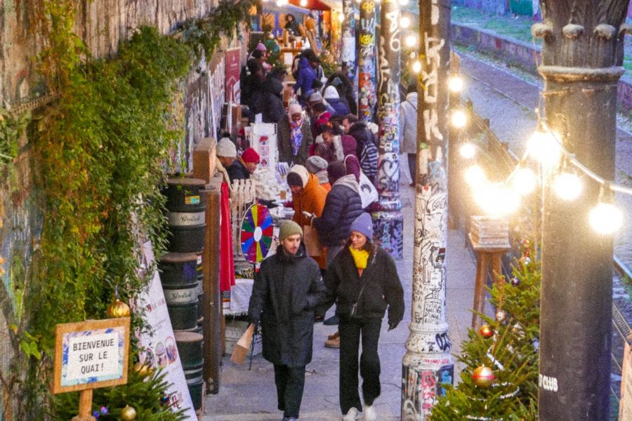 This is an image of a little walkway with nice Christmas stalls and gifts. People are walking past looking.