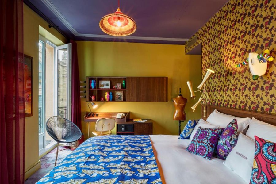 This is an image of a quirky hotel room with mustard yellow wallpaper and mismatched decor that just works.