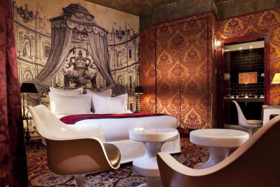 This is an image of a beautiful, artsy room with patterned wallpaper, and chees-piece like coffee tables.
