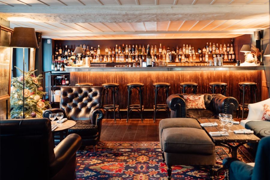 This is an image of a stocked bar and a cozy little room with arm chairs and mood lighting.