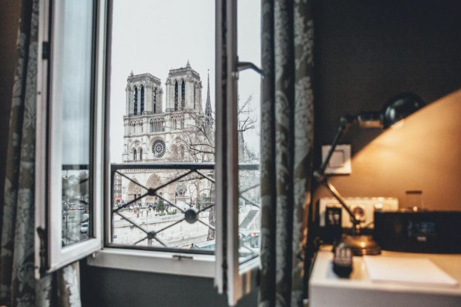 This is an image of a hotel room with a direct view of the Notre Dame Cathedral.