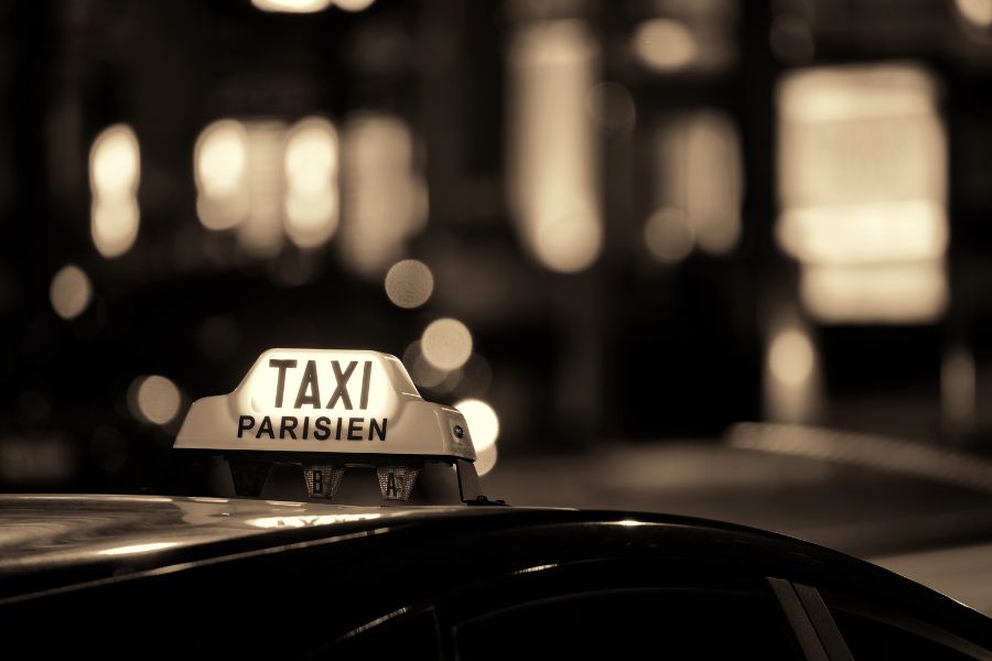 This is an image of a Parisien Taxi in the dark with its light on.