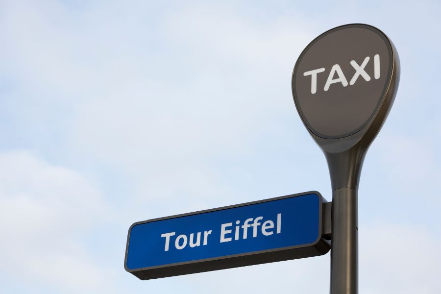 This is an image of a taxi stand that has a sign pointing towards the Eiffel Tower.