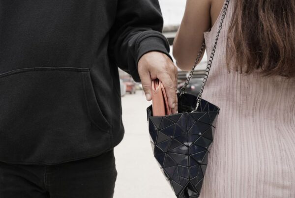 This is an image of a lady wearing a cross body bag and a man coming and taking her purse out of it.